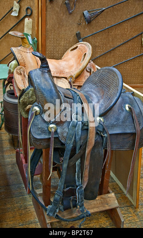 Deux chevaux de selles en cuir brun, l'un et l'autre une couleur havane, sur des tréteaux avec diverses marques de fer. Banque D'Images