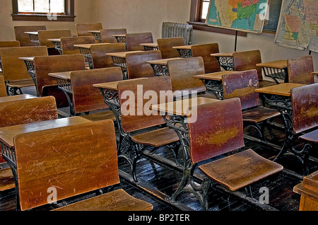 Vintage, début du siècle, ancienne école de classe avec les bureaux en bois, planchers de bois, l'ancien radiateur et vintage cartes. Banque D'Images