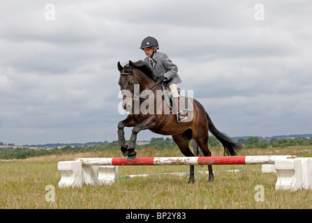 Jeune fille saut à cheval poney club gymkhana concours nord camp UK Cotswolds Banque D'Images