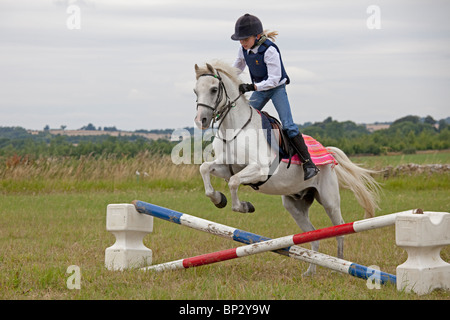 Jeune fille White horse jumping pony club gymkhana UK Cotswolds Nord camp Banque D'Images