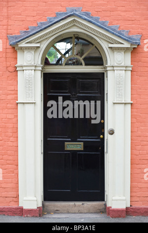 Porte avant en bois noir avec blanc laiton heurtoir letterbox et fronton triangulaire architrave de maison de ville géorgienne en UK Banque D'Images