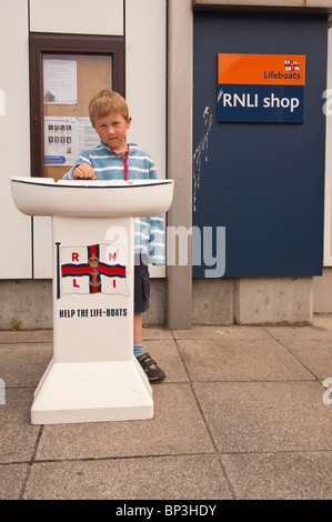 Un modèle publié la photo d'un garçon de 6 ans, mettant l'argent dans un bateau de sauvetage RNLI charité fort à Aldeburgh , Suffolk , Angleterre , Royaume-Uni Banque D'Images