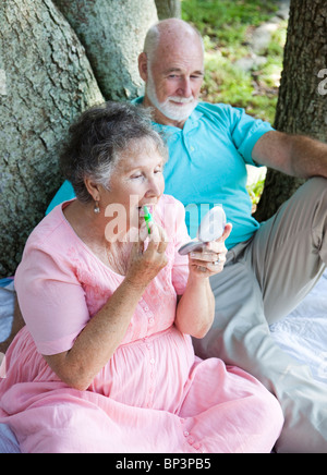 Senior woman sur un pique-nique dans le parc applique le baume de lèvre avec protection solaire. Banque D'Images
