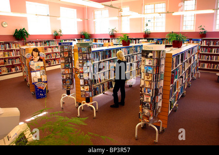 Stockport, Cheshire, Royaume-Uni, du centre-ville, la bibliothèque de Edgeley utilisateur parcourant livres sur des étagères Banque D'Images