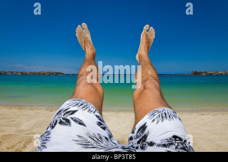 Les jambes d'hommes sur une plage de sable. Banque D'Images