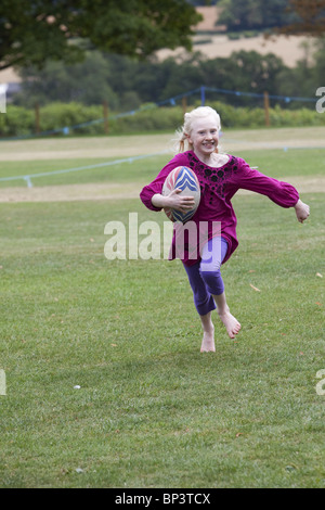 Petite fille blonde à jouer au rugby Banque D'Images