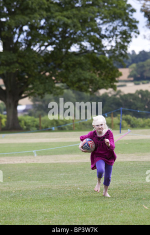 Petite fille blonde à jouer au rugby Banque D'Images