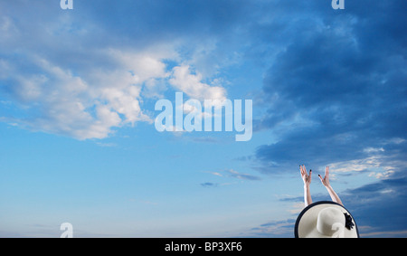 Woman wearing hat atteint ses bras vers le ciel Banque D'Images