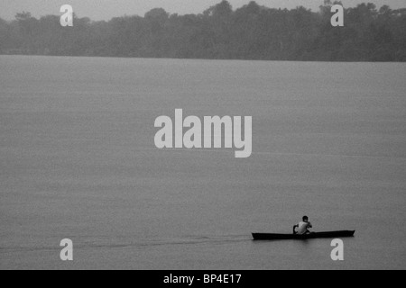 Un jeune indien dans sa pagaie de pirogue d'une seule personne, sur l'amazone, au Brésil. Banque D'Images