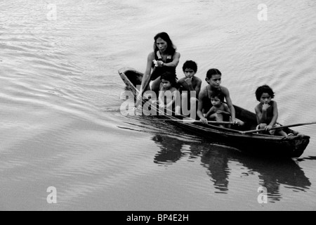 Les enfants indiens avec leur mère dans la pagaie de pirogue sur le fleuve Amazone et la mendicité pour des bonbons. Banque D'Images