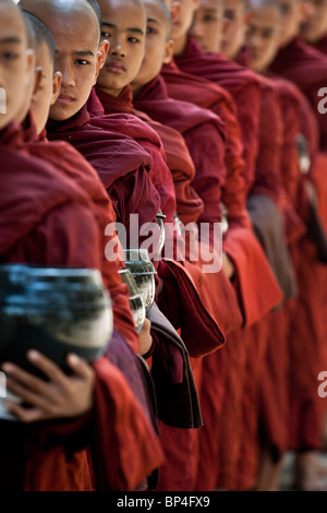Jeunes moines attendre en ligne en attente de recevoir de la nourriture de la communauté autour du monastère Mahagandayon à Amarapura, Myanmar. Banque D'Images