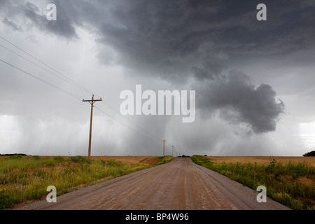 Cumulus qui se profile en colère orage pluie nuages relâchant dans un orage, avec chemin de terre menant à distance Banque D'Images