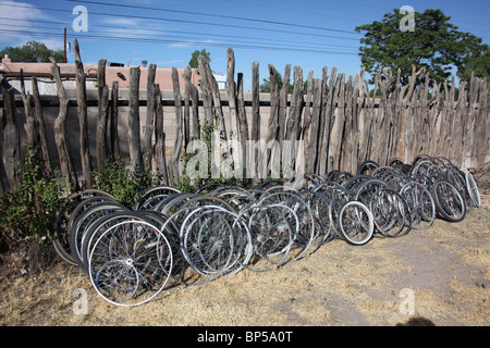 Les roues de bicyclette empilés le long de clôture en bois à l'arrière d'un atelier de réparation de vélos à Corrales, New Mexico, le 10 juin, 2010 Banque D'Images