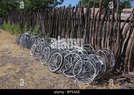 Les roues de bicyclette empilés le long de clôture en bois à l'arrière d'un atelier de réparation de vélos à Corrales, New Mexico, le 10 juin, 2010 Banque D'Images