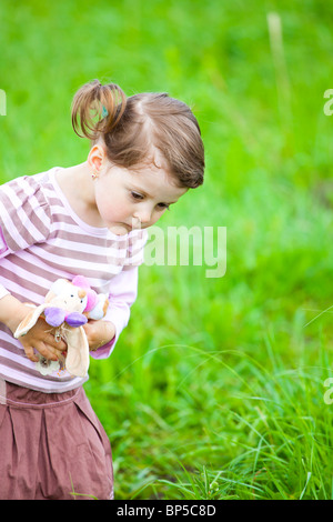 Petite fille à la curiosité sur une pelouse. Banque D'Images