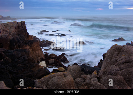 Une exposition plus longue shot montre de grandes vagues se briser sur la plage avec des rochers au premier plan détaillé la scène de cadrage Banque D'Images