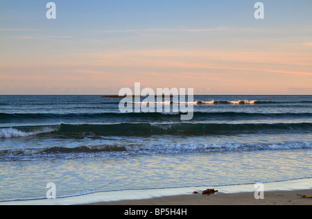 Marée montante à Bigbury-on-Sea, South Hams, Devon. La dernière lumière du soleil dore les bords des brisants sur la plage. Banque D'Images