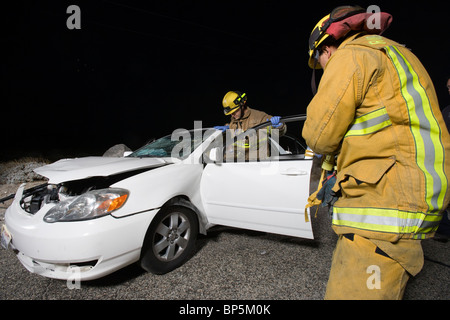 Examiner les pompiers voiture après accident Banque D'Images