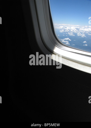 Vue d'un passager d'un avion à l'extérieur de la fenêtre avec la lumière du jour, ciel bleu et nuages Banque D'Images
