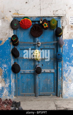 Chapeaux colorés et à la vente de l'EAPV, suspendu à une porte bleue à Stone Town, Zanzibar, Tanzanie Banque D'Images