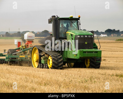 John Deere tracteur à chenilles en caoutchouc de briser le sol prêt pour le labour après la récolte de maïs dans un champ de Norfolk Banque D'Images