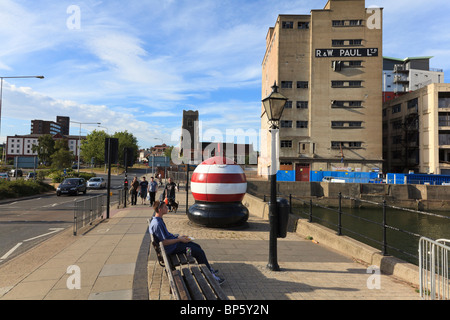 Un garçon est assis et mange sur un pont au-dessus de la rivière Orwell à Ipswich, derrière lui, un grand rouge et blanc à rayures bouée, Ipswich, Suffolk, UK Banque D'Images
