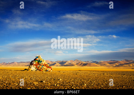 Les drapeaux de prières l'étouffement un rocher au bord du lac Namsto, en face de la montagne, Tibet Nyainqêntanglha Banque D'Images