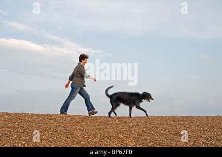 Femme promener son chien le long du littoral du patrimoine de Suffolk Banque D'Images