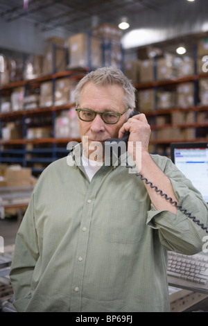 Homme sérieux à l'aide de téléphone dans l'entrepôt de distribution Banque D'Images