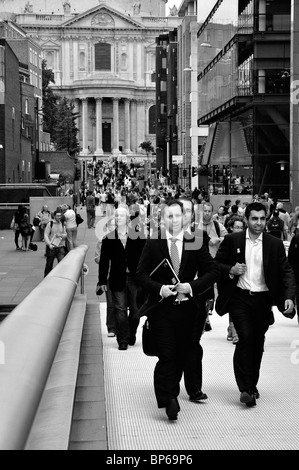 Les hommes d'affaires dans les suites de marcher à travers Millennium Bridge, Londres Banque D'Images