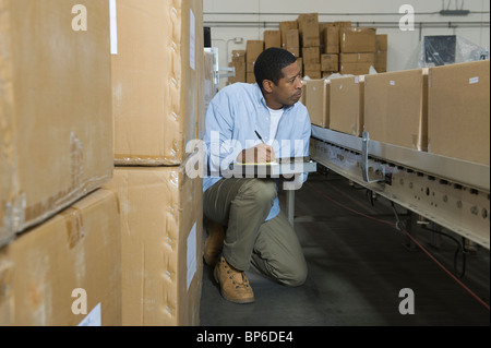 Boîtes d'inspection de l'homme sur la courroie du convoyeur en entrepôt de distribution Banque D'Images