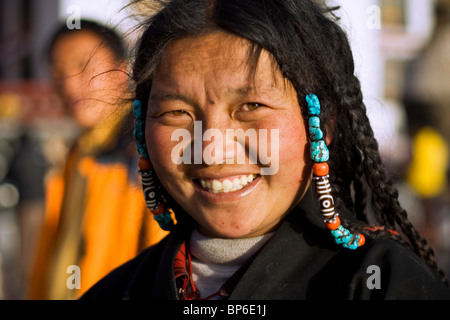 Une jolie femme tibétaine traditionnelle en tête et sourit dans la robe de cheveux Quartier du Barkhor, Lhassa, Tibet, Chine. Banque D'Images