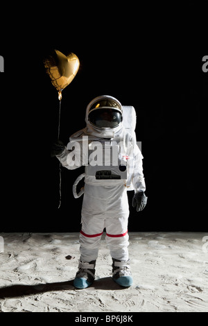 Un astronaute sur la lune tenant un ballon hélium en forme de coeur Banque D'Images