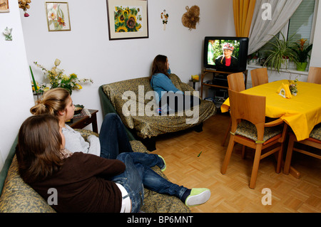 Trois filles assis devant la télévision à la maison en Autriche Banque D'Images