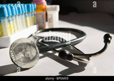 Un stéthoscope avec un billet d'un dollar sur elle et de la médecine dans l'arrière-plan Banque D'Images