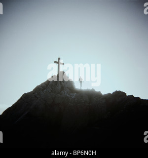 Une personne debout au-dessous d'un crucifix sur le sommet d'une montagne, le Mont Saint Michel, Normandie, France Banque D'Images