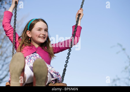 Une jeune fille assise sur une balançoire Banque D'Images