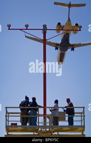 Les personnes travaillant sur la piste sous les feux d'approche d'avion à réaction à l'atterrissage à Los Angeles Int'l Airport, Californie Banque D'Images