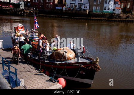 Les gens obtenant sur boat docked in harbour, Whitby, North Yorkshire, Angleterre. Banque D'Images