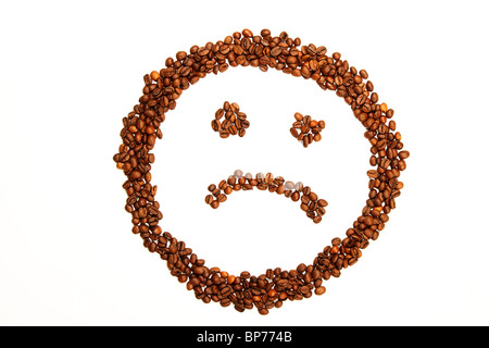 Smiley triste faite de grains de café sur fond blanc Banque D'Images