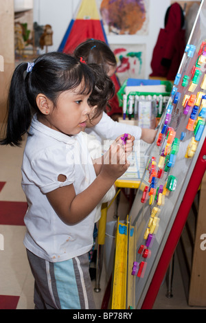 4 ans preschool girl putting lettres magnétiques sur une carte Banque D'Images