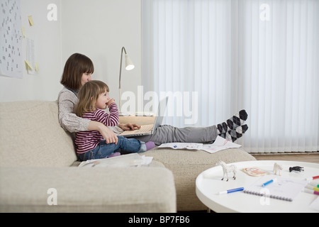 Mère et fille avec un ordinateur portable dans la salle de séjour Banque D'Images