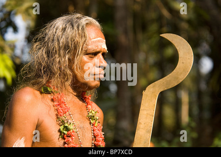 Un homme porte un sabre de cérémonie tandis que dans le rôle de Velichappad lors d'une procession à Olappamanna Mana dans le Kerala, Inde Banque D'Images