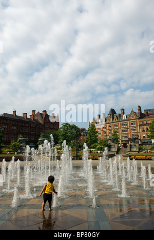 Un enfant joue dans la fontaine à la Peace Gardens, Sheffield, South Yorkshire, Angleterre Banque D'Images