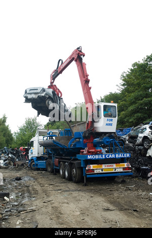 L'homme travaillant sur un crane grab dans un parc à ferraille recyclage voitures UK Banque D'Images