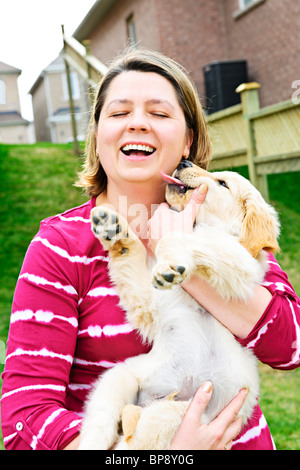 Portrait of laughing woman holding chiot golden retriever Banque D'Images