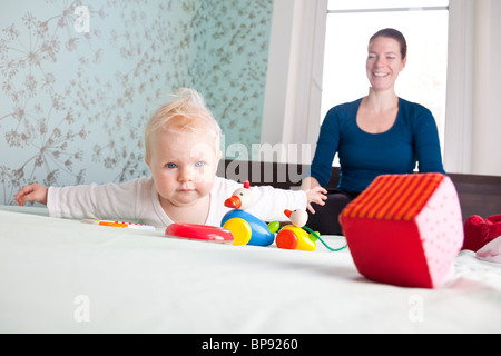 Bébé (7 mois) qui se trouve à l'avant, la mère en arrière-plan, Leipzig, Saxe, Allemagne Banque D'Images