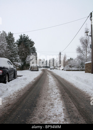 La neige épaisse et pistes de voiture sur une route de la région des Cotswolds Banque D'Images