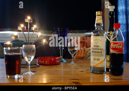 L'homme ivre dormir à une table avec des bouteilles d'alcool, Berlin, Allemagne Banque D'Images