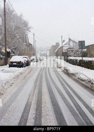 La neige épaisse et pistes de voiture sur une route de la région des Cotswolds Banque D'Images